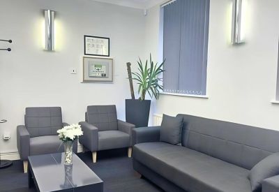 Modern lounge area with two gray armchairs, a matching sofa, and a black coffee table.