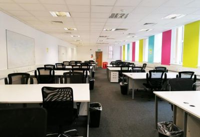 Spacious open-plan office with colorful vertical window blinds and rows of white desks.