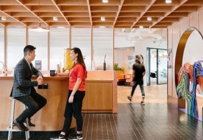 Meeting space with a wood-slat ceiling, circular doorway, and people talking at a high counter.