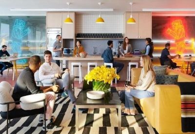 Vibrant kitchen and breakout area with a striped rug, yellow flowers, and people socializing.