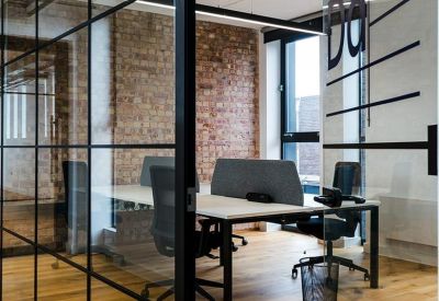Meeting room with a white desk and black chairs behind a black-framed glass partition.