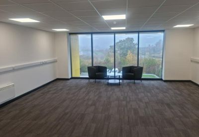 Bright breakout area featuring two comfortable black armchairs and views through large windows.