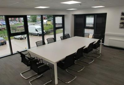 Spacious meeting room with a large white table, black chairs, and floor-to-ceiling windows.
