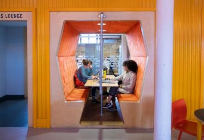 Unique orange hexagonal-shaped meeting pod with central table and seating.