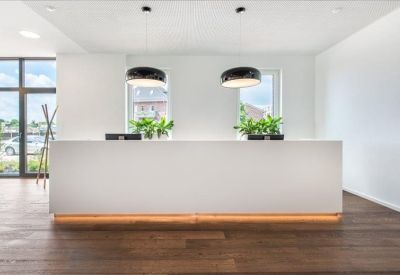 Sleek white reception desk featuring warm under-lighting and potted plants.