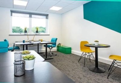 Contemporary breakout space with teal and yellow chairs, a small round table, and a geometric teal wall feature.