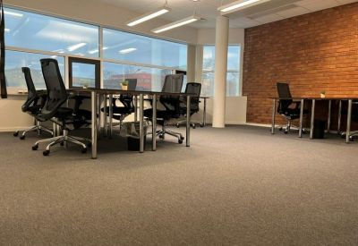 Open-plan workspace featuring multiple desks and an accent brick wall.