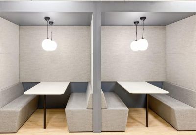 Two acoustic-paneled meeting booths with white tables and hanging globe lights.