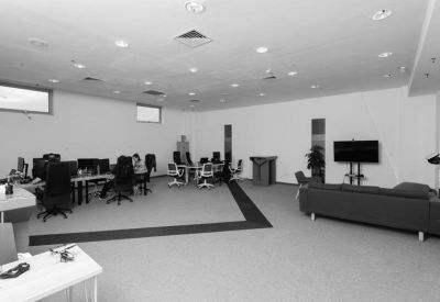 Modern open-plan office featuring a lounge area with a dark sofa and television.