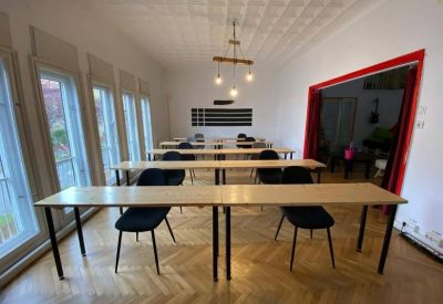 Bright classroom style meeting room with long wooden tables and black chairs.