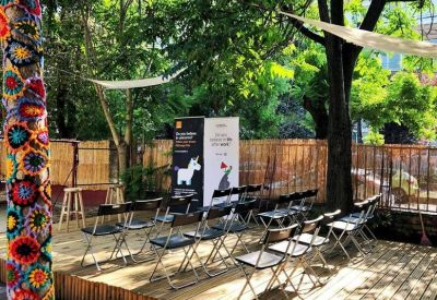 Outdoor presentation space with rows of chairs on a wooden platform and a decorated tree trunk.