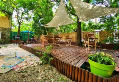 Outdoor wooden deck area with sun sails and green potted plants.