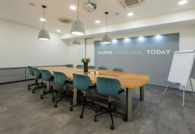 Meeting room with a long wooden table, teal chairs, and an inspirational wall graphic.
