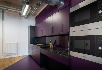 Modern communal kitchen featuring bold purple cabinetry and integrated black appliances.
