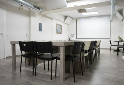 Modern conference room featuring a large projection screen and black seating.