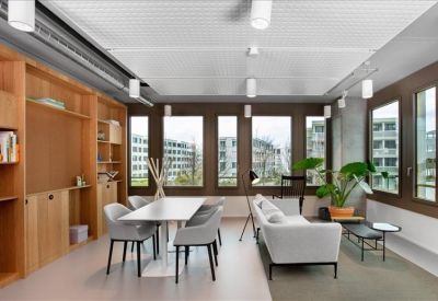 Comfortable lounge area with a grey sofa, wooden shelving, and large windows.