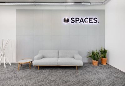 Minimalist reception area with a light grey sofa and branded signage.