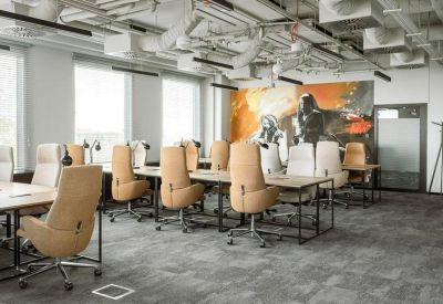 Modern office floor with ergonomic tan chairs and a vibrant orange wall graphic.