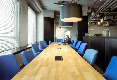 Bright conference room featuring a long light-wood table and blue chairs.