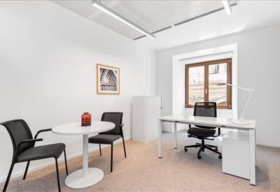 Private office suite with a round guest table and a white desk by a window.