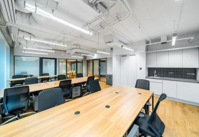 Professional boardroom with a light wood table, black ergonomic chairs, and integrated kitchenette.