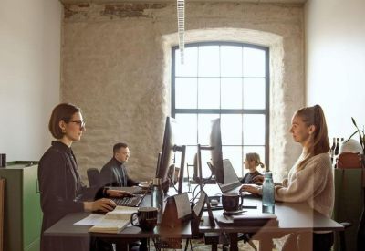 Modern open-plan office with people working at height-adjustable standing desks.