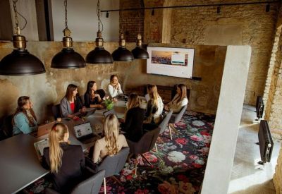 Professional meeting room with a large table, black pendant lights, and exposed stone walls.