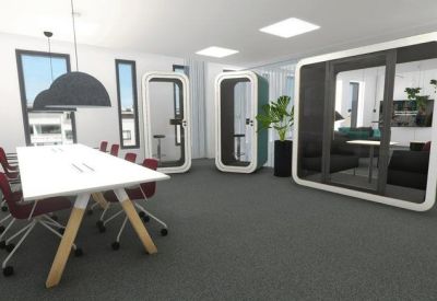 Meeting room with a large white table, red chairs, and soundproof phone booths.