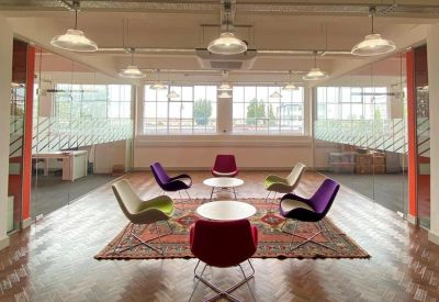 Breakout area with a colorful rug, assorted chairs, and wood flooring.