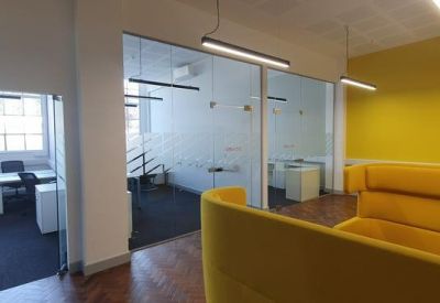 Breakout zone with bright yellow walls and matching high-back privacy sofas.