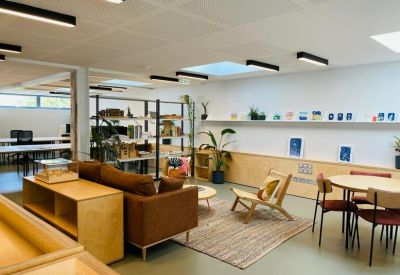 Spacious communal lounge area with a brown sofa, wooden coffee table, and shelving unit.