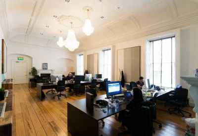 Elegant open-plan office with high ceilings, chandeliers, and large windows.