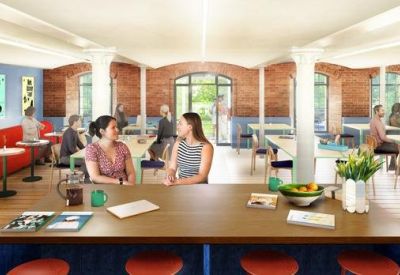 Bright communal lounge and cafe area with wooden floors, brick walls, and various seating arrangements.