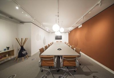 Large professional boardroom with a long white table and feature orange wall.