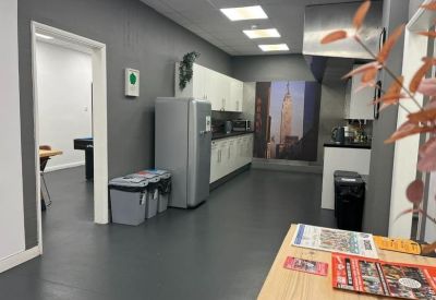 Modern kitchen and breakout area with grey walls and a city skyline mural.