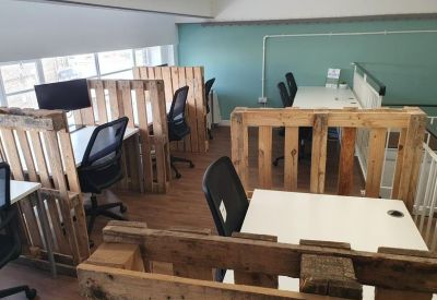 Open-plan workspace with desks separated by rustic wooden pallet partitions.