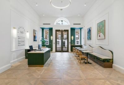 Bright reception area featuring a green desk and decorative wood flooring.