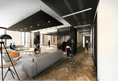 Spacious communal lounge with grey sofas, wooden herringbone flooring, and high ceilings.