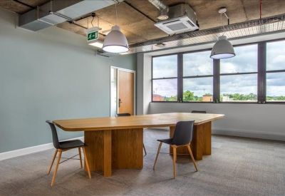 Spacious communal area featuring a long wooden table, black chairs, and industrial-style ceiling.