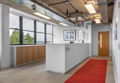 Bright reception area with a white front desk and a red runner carpet.