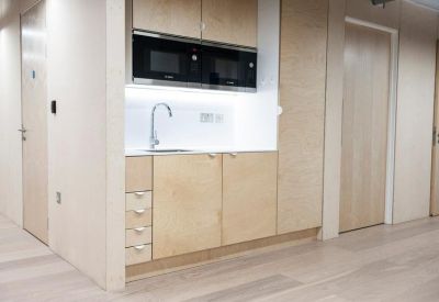 Modern kitchenette with light wood cabinetry and integrated appliances.