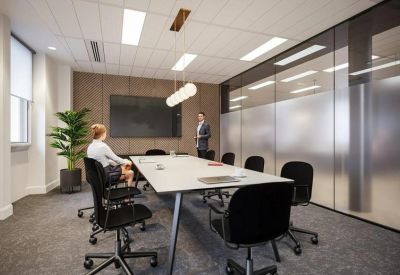 Professional meeting room with a long white table, black rolling chairs, and frosted glass walls.