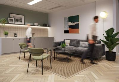 Cozy breakout kitchen area with a grey sofa, olive green chairs, and a herringbone floor.