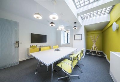 Modern meeting room with a white table, lime green chairs, and a unique skylight ceiling.