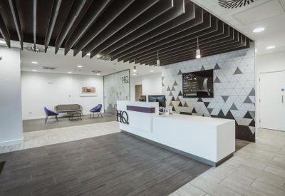 Reception area with a modern desk, geometric wall graphics, and slatted ceiling feature.