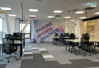 Wide open-plan workspace with multiple desks and a colorful motivational wall mural.