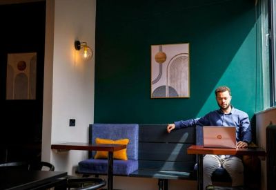 Individual workspace featuring a man on a laptop in a private booth with a deep green feature wall.
