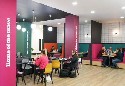 Vibrant communal break area with pink feature walls, colorful seating, and modern pendant lighting.