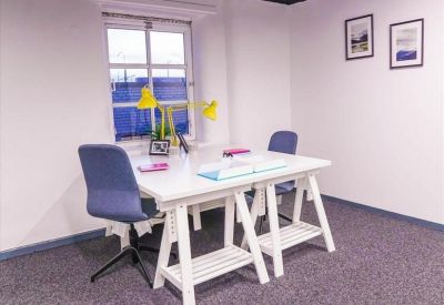 Bright private office suite with two white desks and blue ergonomic chairs.