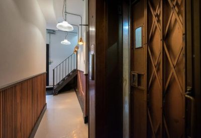 Building interior featuring a classic gated lift and wood-paneled hallway leading to a staircase.